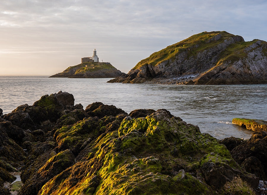 Mumbles Lighthouse on the island off Mumbles Head lit by the early morning light.