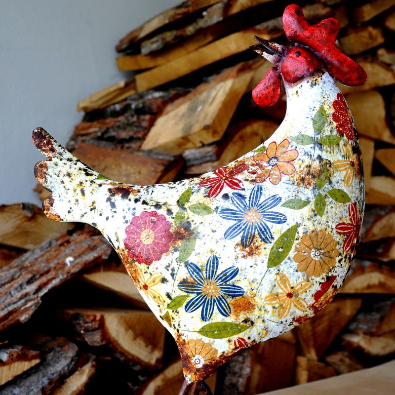 Metal chicken with a floral print on a white chicken with red features.