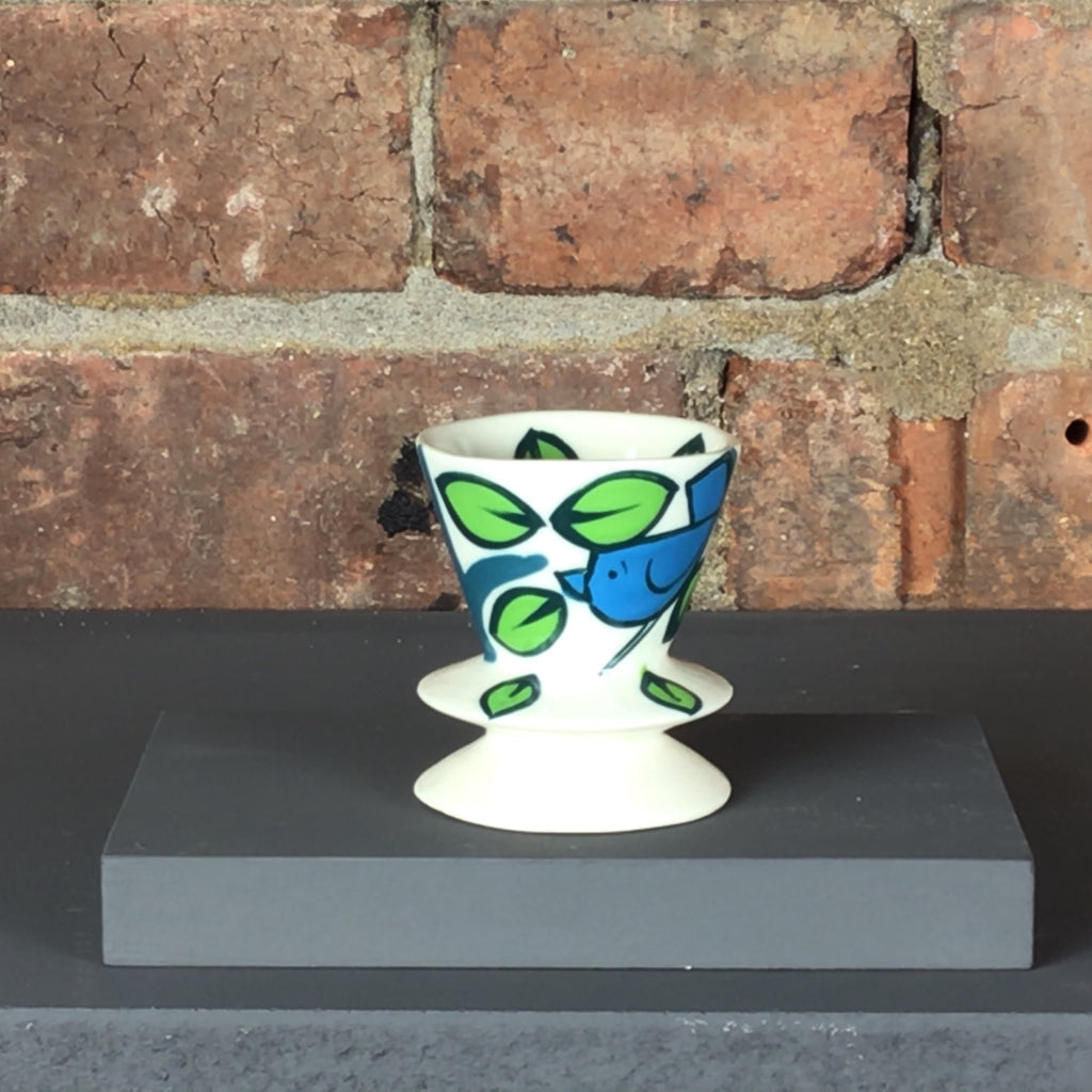 White egg cup with blue and green bird and leaves design.