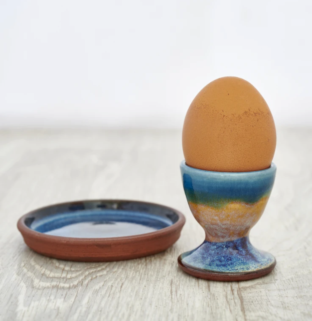 Ceramic egg cup and saucer in pale blue and yellow.