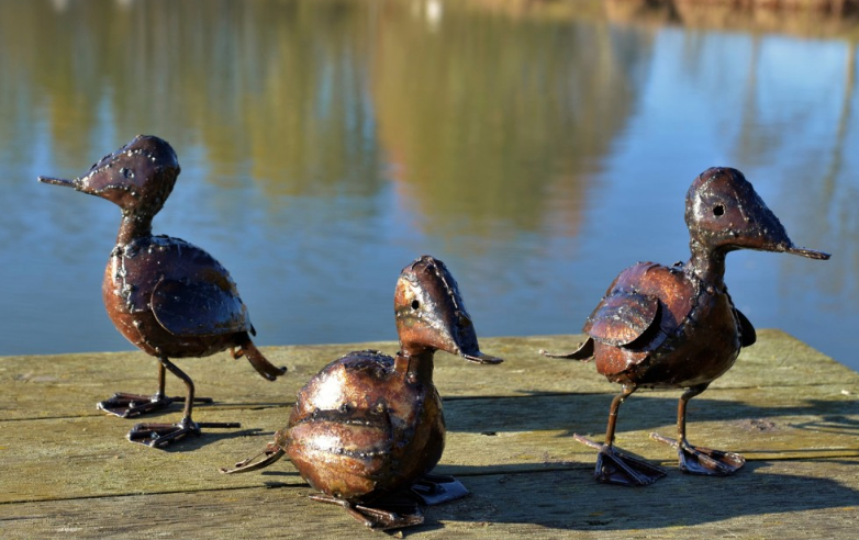 Metal ducklings in rusted brown colour.
