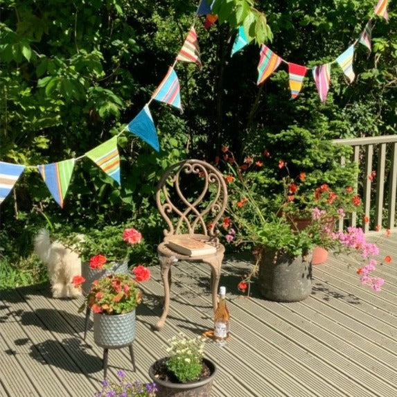 Multicoloured stripy cotton bunting hanging in a garden