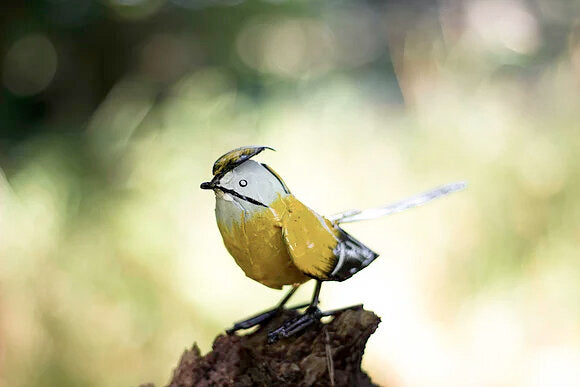 Recycled metal waxwing bird in yellow.